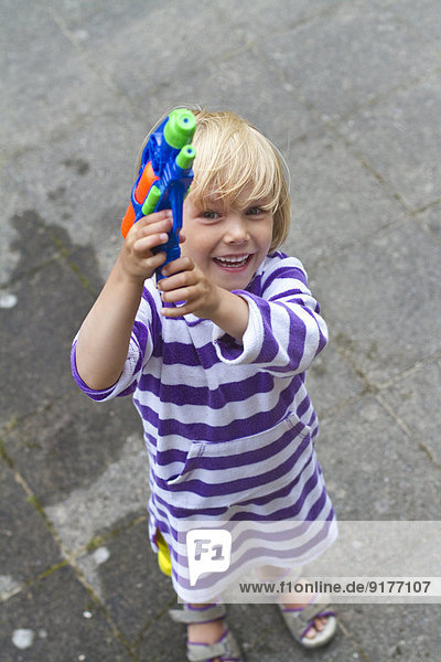 Little girl having fun with water pistol