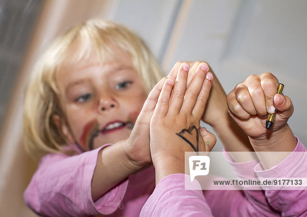 Little girl painting a heart on her hand