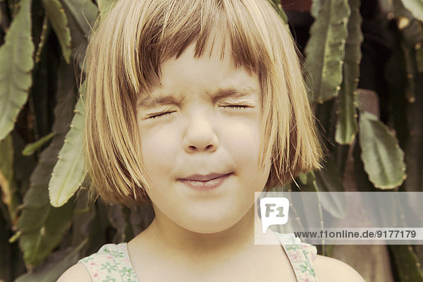 Porträt eines kleinen Mädchens mit geschlossenen Augen und schmollendem Mund