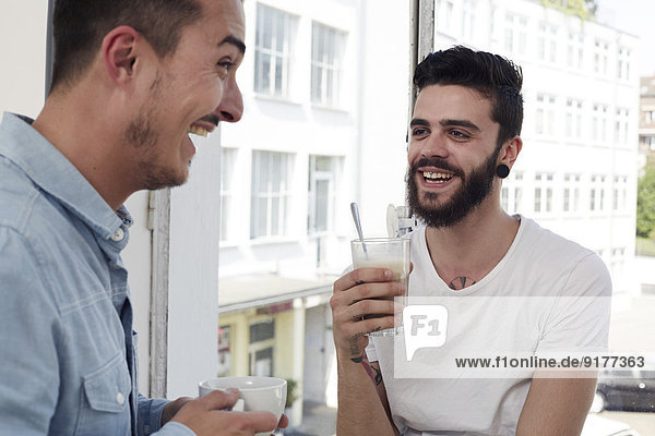 Two laughing men having coffee break in office