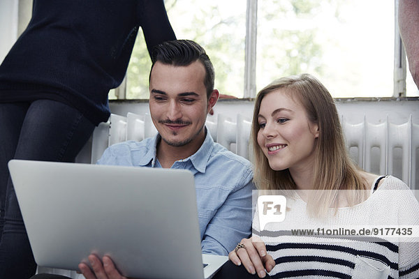 Smiling man and woman using laptop