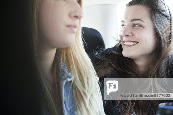 Zwei junge Frauen  die auf dem Rücksitz eines Autos sitzen.