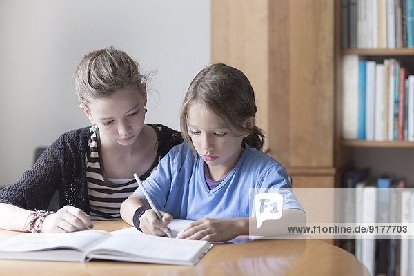 Schwester hilft ihrem kleinen Bruder,  indem sie seine Hausaufgaben macht.