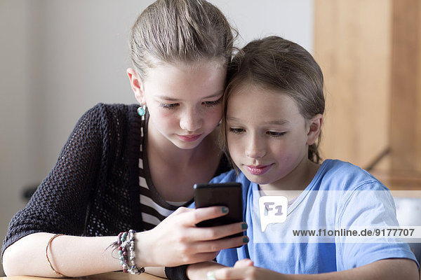 Porträt von Geschwistern beim Betrachten von Smartphones zu Hause