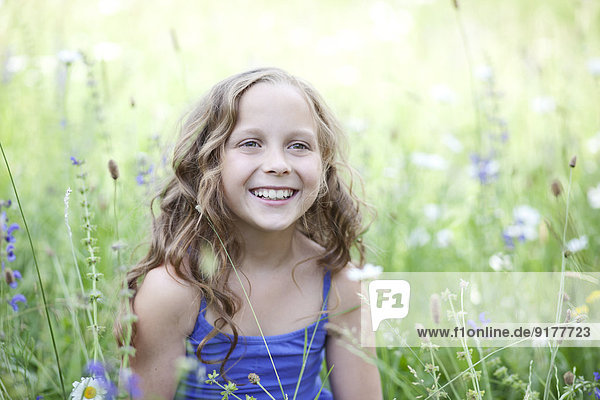 Portrait of smiling girl sitting on flower meadow