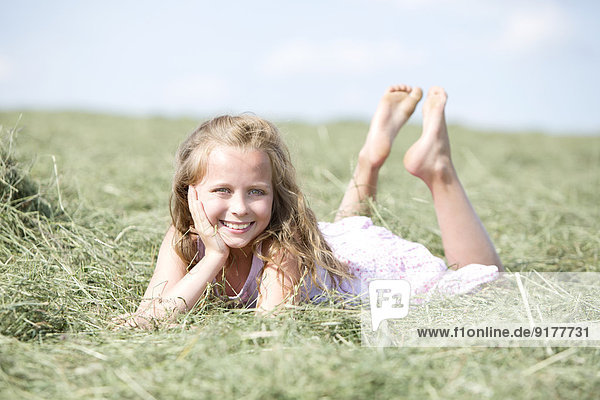Germany  Bavaria  Young girl lying on meadow with hay