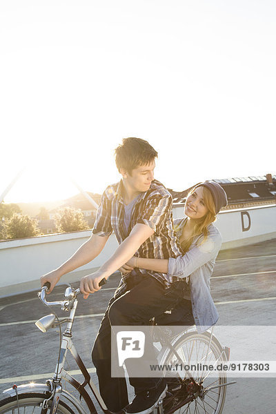 Happy teenage couple outdoors on bicycle