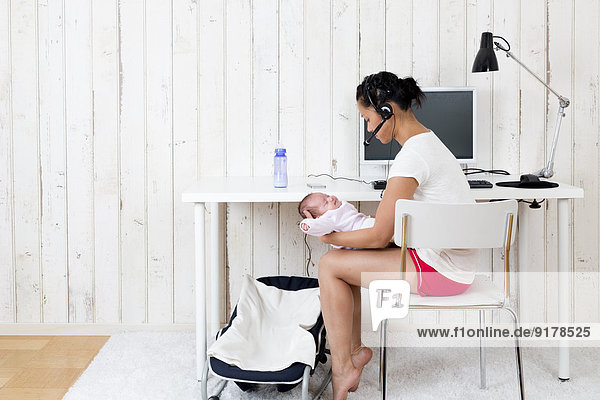 Frau im Home-Office mit ihrem Baby