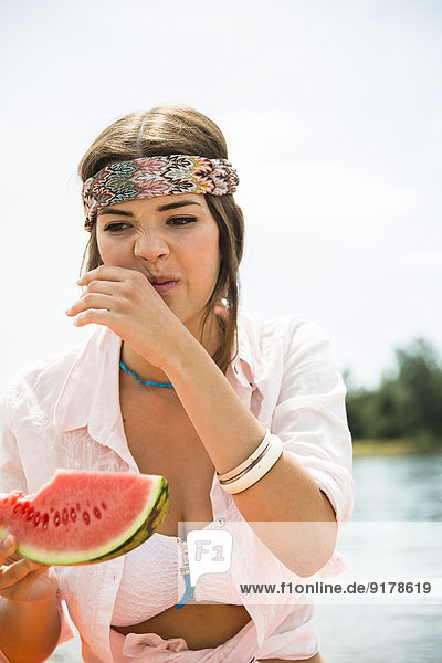 Porträt einer jungen Frau  die Wassermelone am Strand isst.