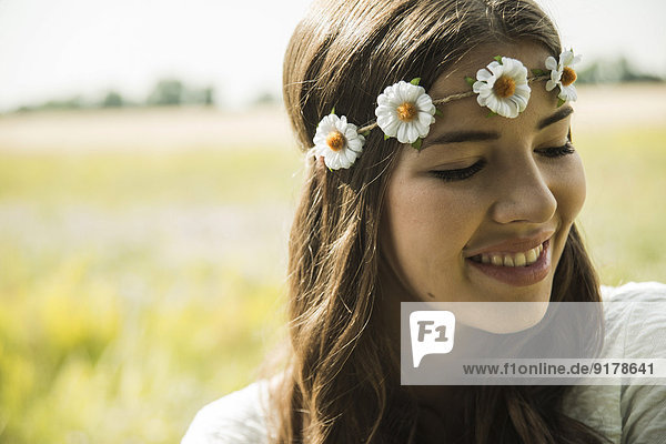 Porträt einer lächelnden jungen Frau mit Blumenkranz