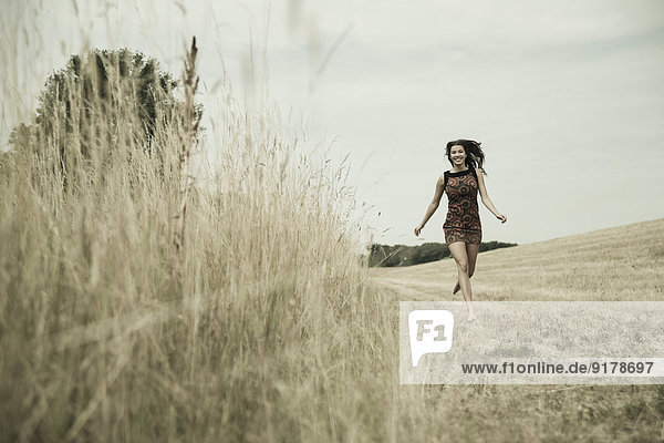 Young woman running on a harvested meadow