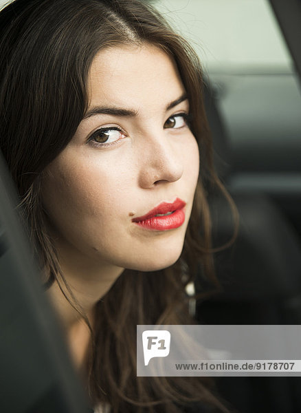 Portrait of young woman with red lips sitting in car
