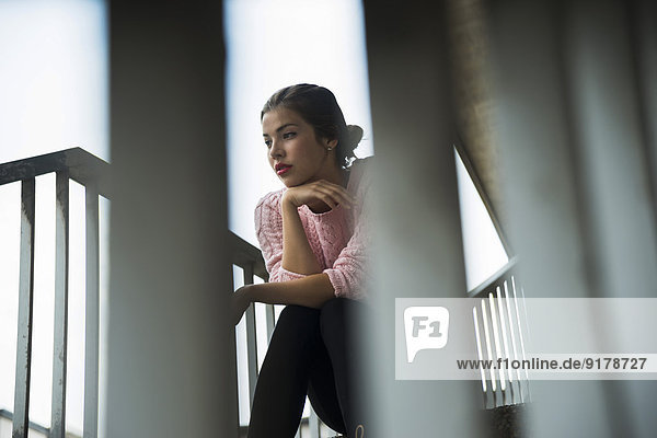 Young woman sitting on stairs watching something