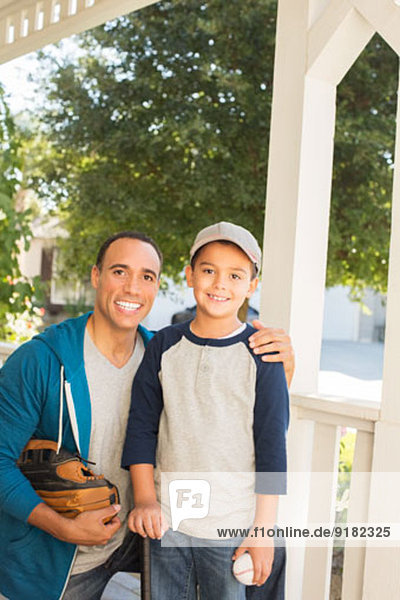 Porträt von Vater und Sohn mit Baseball und Handschuh auf der Veranda