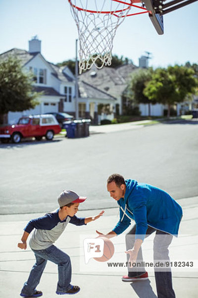 Vater und Sohn spielen Basketball in der Einfahrt