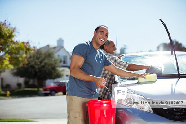 Vater und Sohn waschen Auto in der Einfahrt