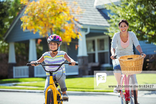 Mutter und Tochter beim Radfahren in der sonnigen Straße