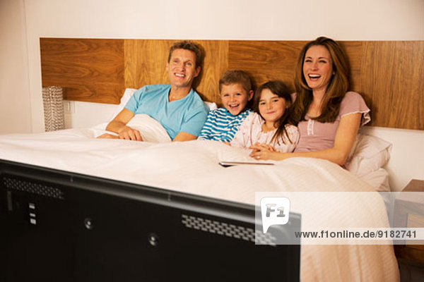 Familie beim Fernsehen im Bett