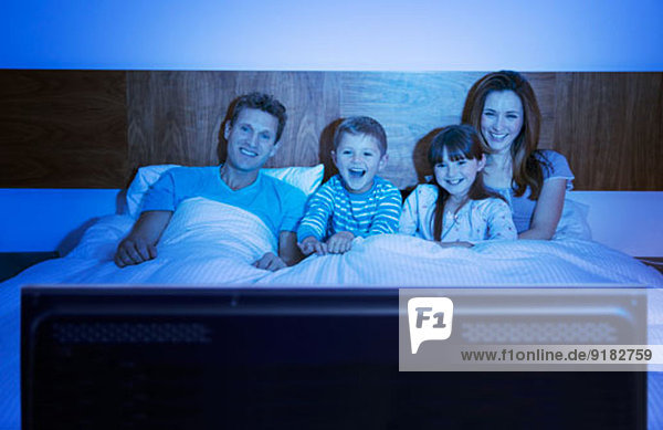 Familie beim Fernsehen im Bett