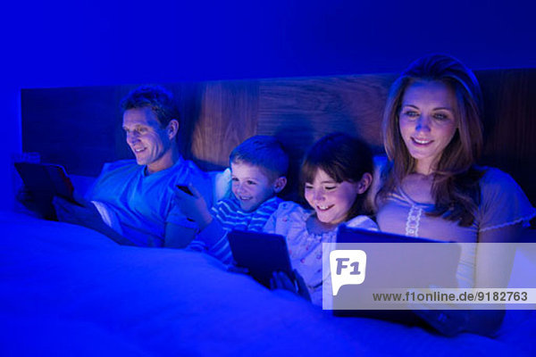 Familie mit Technik im Bett