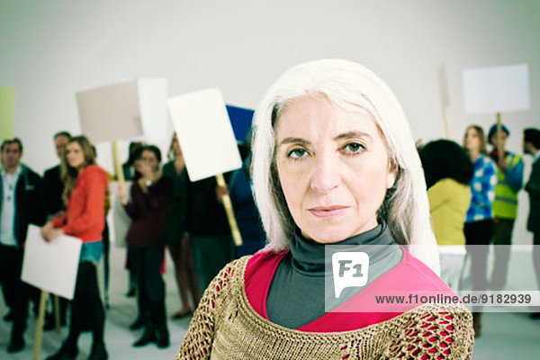 Porträt einer ernsten Frau mit Protestierenden im Hintergrund