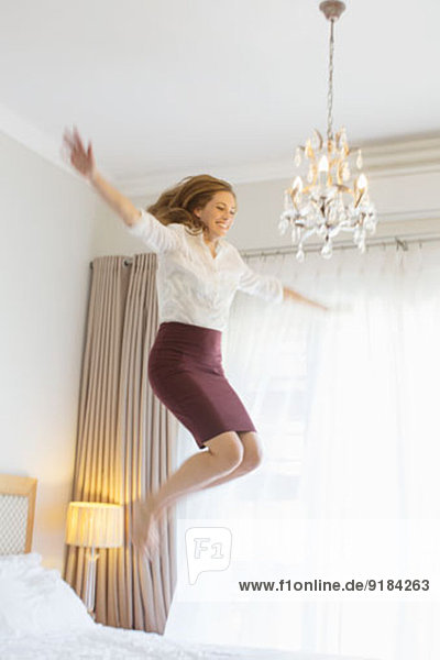 Geschäftsfrau springt auf Bett im Hotelzimmer