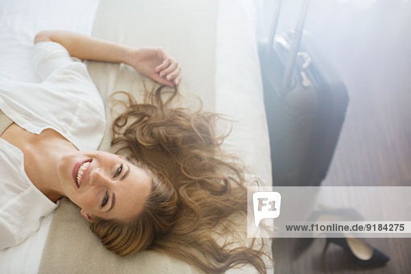 Geschäftsfrau im Hotelzimmer auf dem Bett liegend