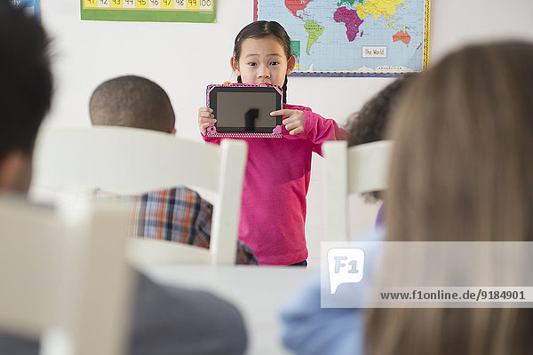 Girl showing digital tablet to classroom