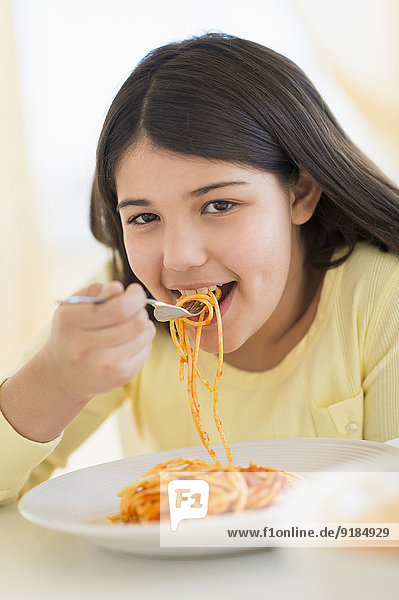 Hispanic girl eating plate of pasta