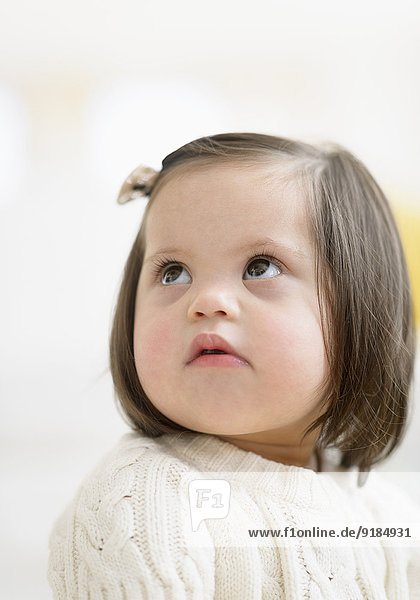 Hispanic toddler with Down syndrome looking up
