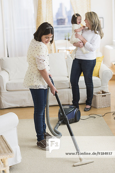 Hispanic girl vacuuming living room