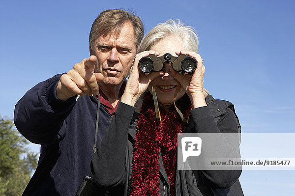 Senior Caucasian couple using binoculars outdoors