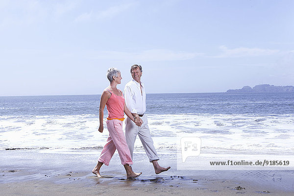 Senior Caucasian couple walking on beach