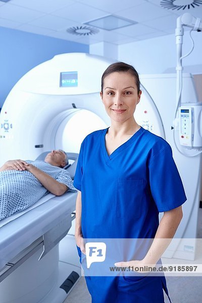 Der Röntgentechniker steht vor dem Mann  der in den CT-Scanner geht.