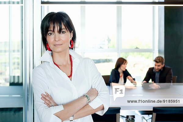 Businesswoman at entrance of meeting room  couple in background