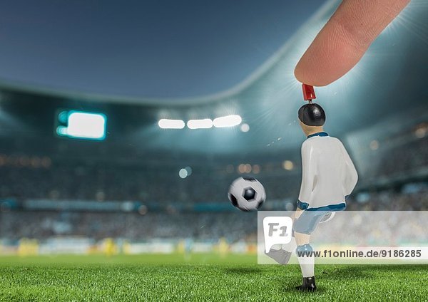 Digital erzeugtes Bild eines Fußballspielers  der den Ball im beleuchteten Stadion kickt.