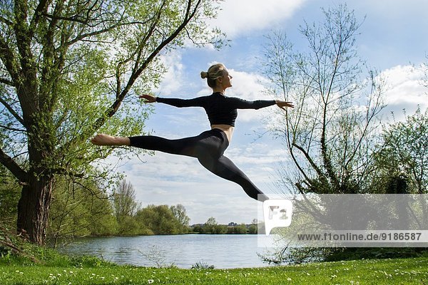 Junge Tänzerin beim Springen in der Luft am See