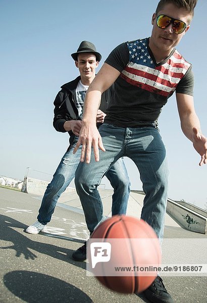 Young men playing basketball in skatepark