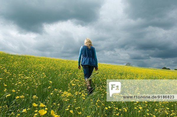 Woman walking in field of buttercups