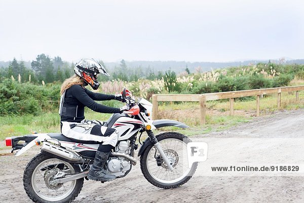 Mid adult female motorcyclist riding on dirt track