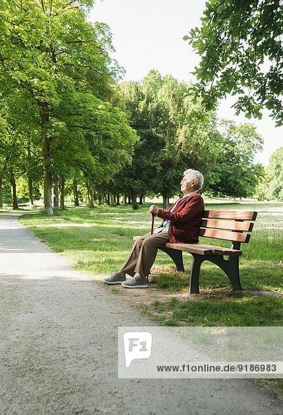 Senior woman sitting on park bench in park