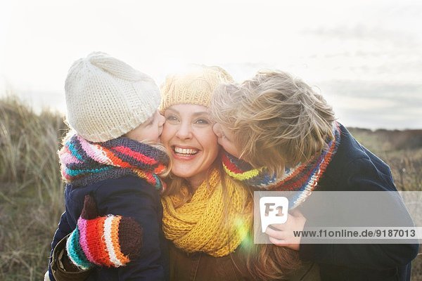 Mittlere erwachsene Frau mit Sohn und Tochter  die ihre Wange an der Küste küssen.