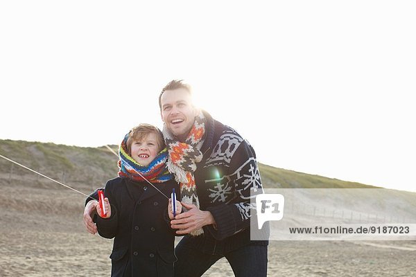 Mid adult man flying kite mit Sohn am Strand  Bloemendaal aan Zee  Niederlande