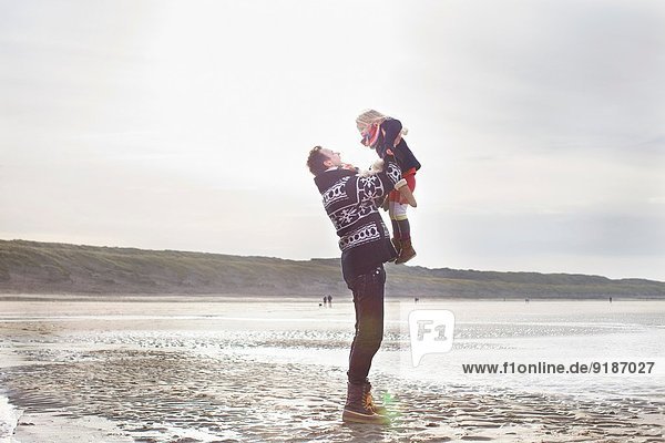 Mittlerer Erwachsener Mann  der seine Tochter am Strand aufhebt  Bloemendaal aan Zee  Niederlande