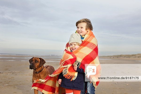Porträt eines dreijährigen Mädchens und Bruders in Decke am Strand  Bloemendaal aan Zee  Niederlande