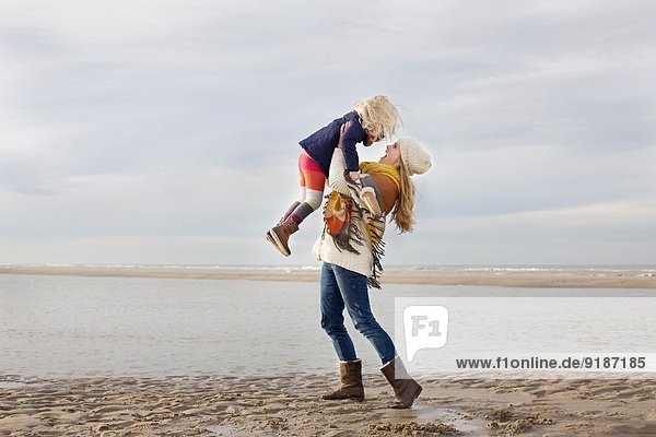 Mittlere erwachsene Frau  die ihre Tochter am Strand aufhebt  Bloemendaal aan Zee  Niederlande