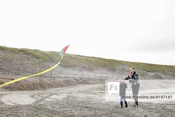 Mid adult man and son flying kite on beach  Bloemendaal aan Zee  Netherlands