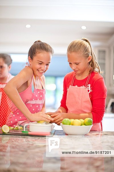 Zwei Teenager-Mädchen  die Zitronen in der Küche quetschen