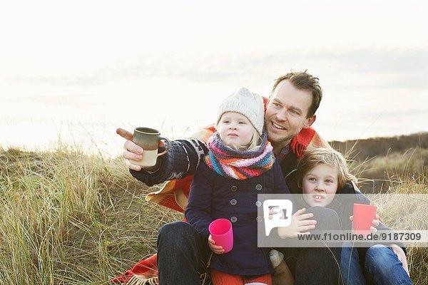 Lächelnder erwachsener Mann mit Tochter und Sohn auf Sanddünen