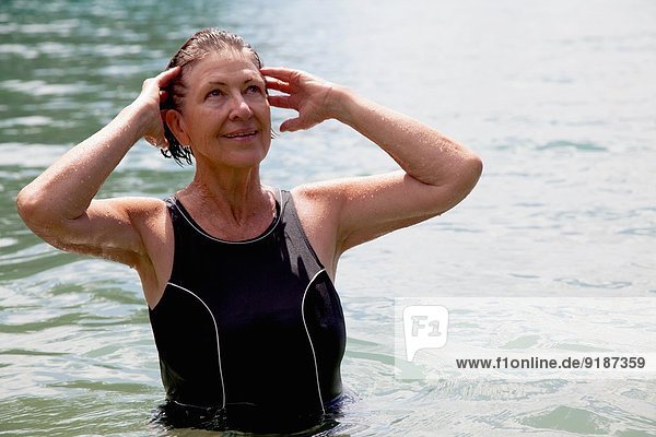 Seniorenschwimmerin mit Händen in nassem Haar
